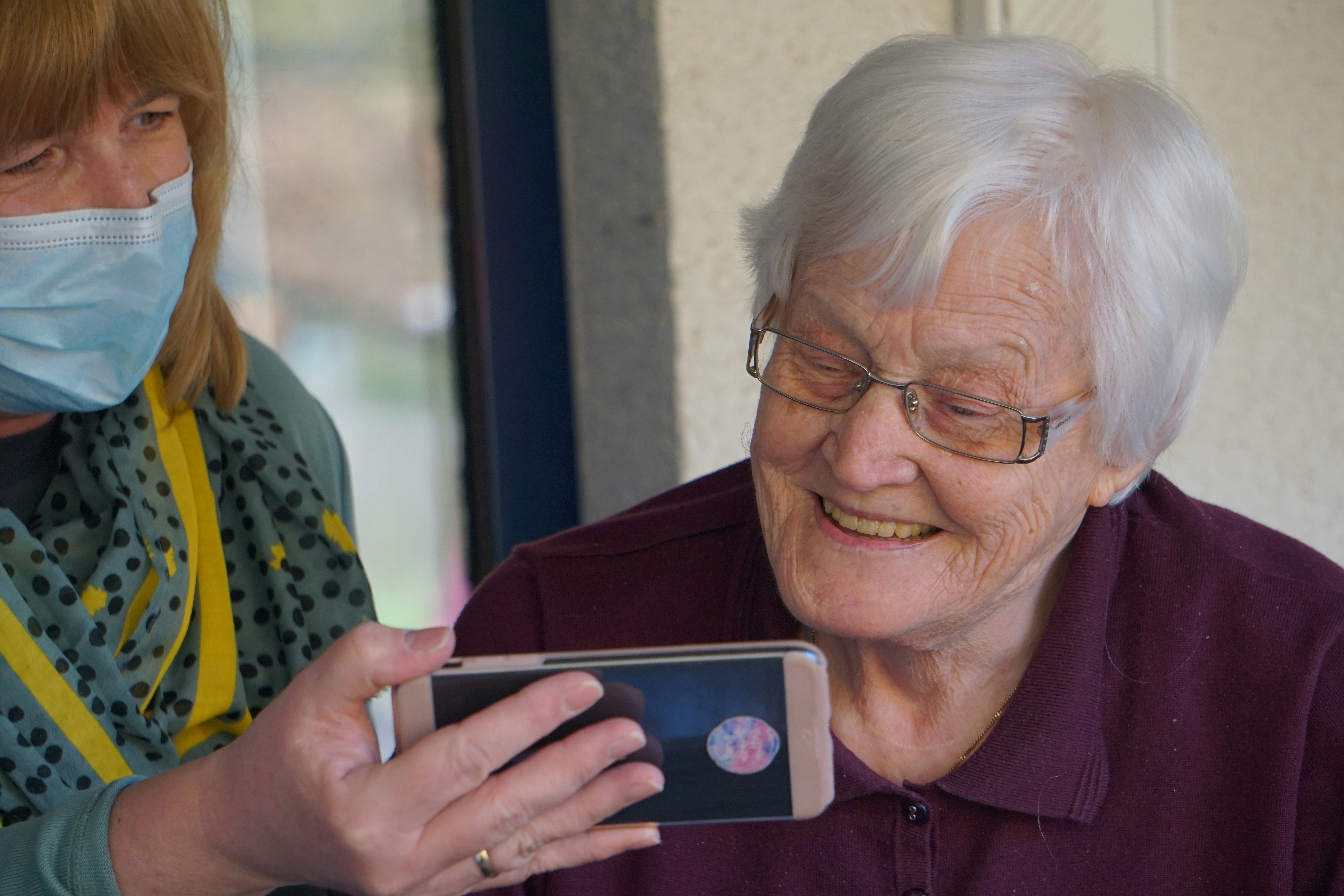 A granddaughter showing her grandmother how to use a phone — the quiet moment code:blue is designed to protect.